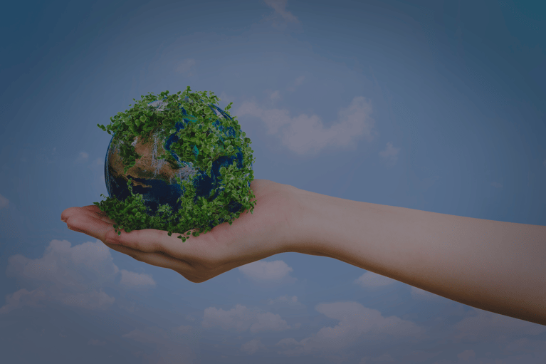 Globe with foliage on an oustretched palm of hand with a blue sky with clouds background.